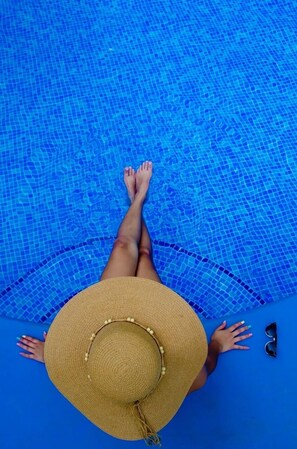 A person lying in a pool with a straw hat and sunglasses beside them. - Hotel & Villas Huetares (Sardinal)