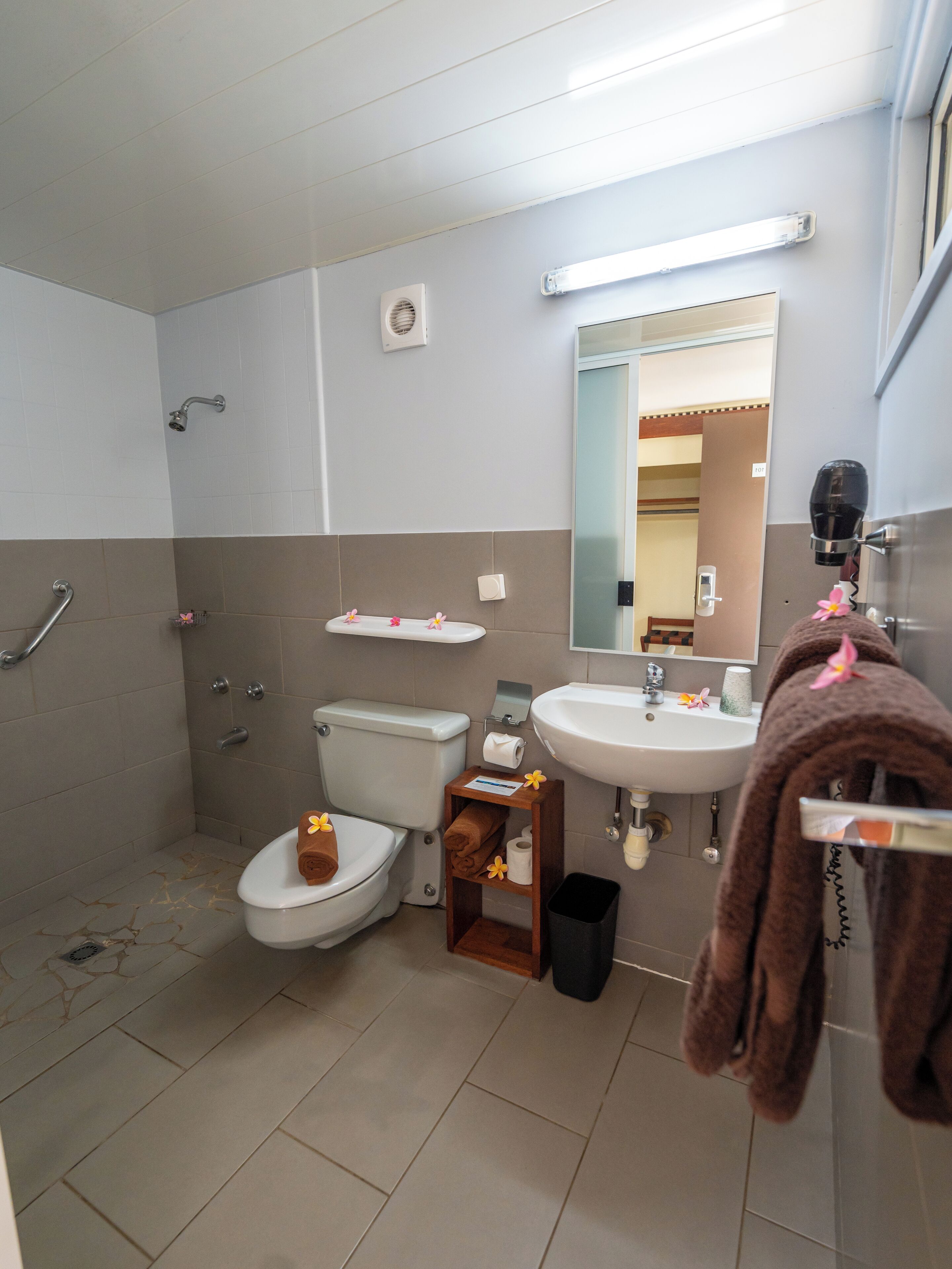 A bathroom with a toilet, sink, and shower. There is a towel rack with a towel hanging on it.