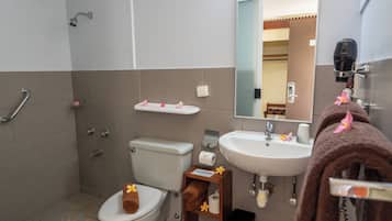 A bathroom with a toilet, sink, and shower. There is a towel rack with a towel hanging on it.