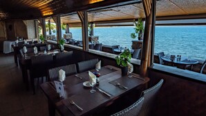 A restaurant with tables set for dining, overlooking a body of water. - Hotel Royal Tahitien (Pirae)