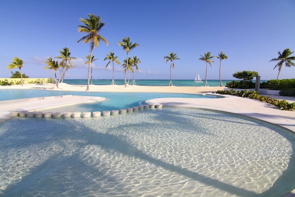 Una piscina al aire libre, sombrillas, sillones reclinables de piscina