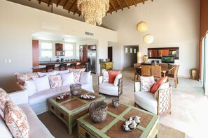 Uma sala de estar ampla com um sofá grande, uma mesa de centro e uma área de jantar com mesa e cadeiras.