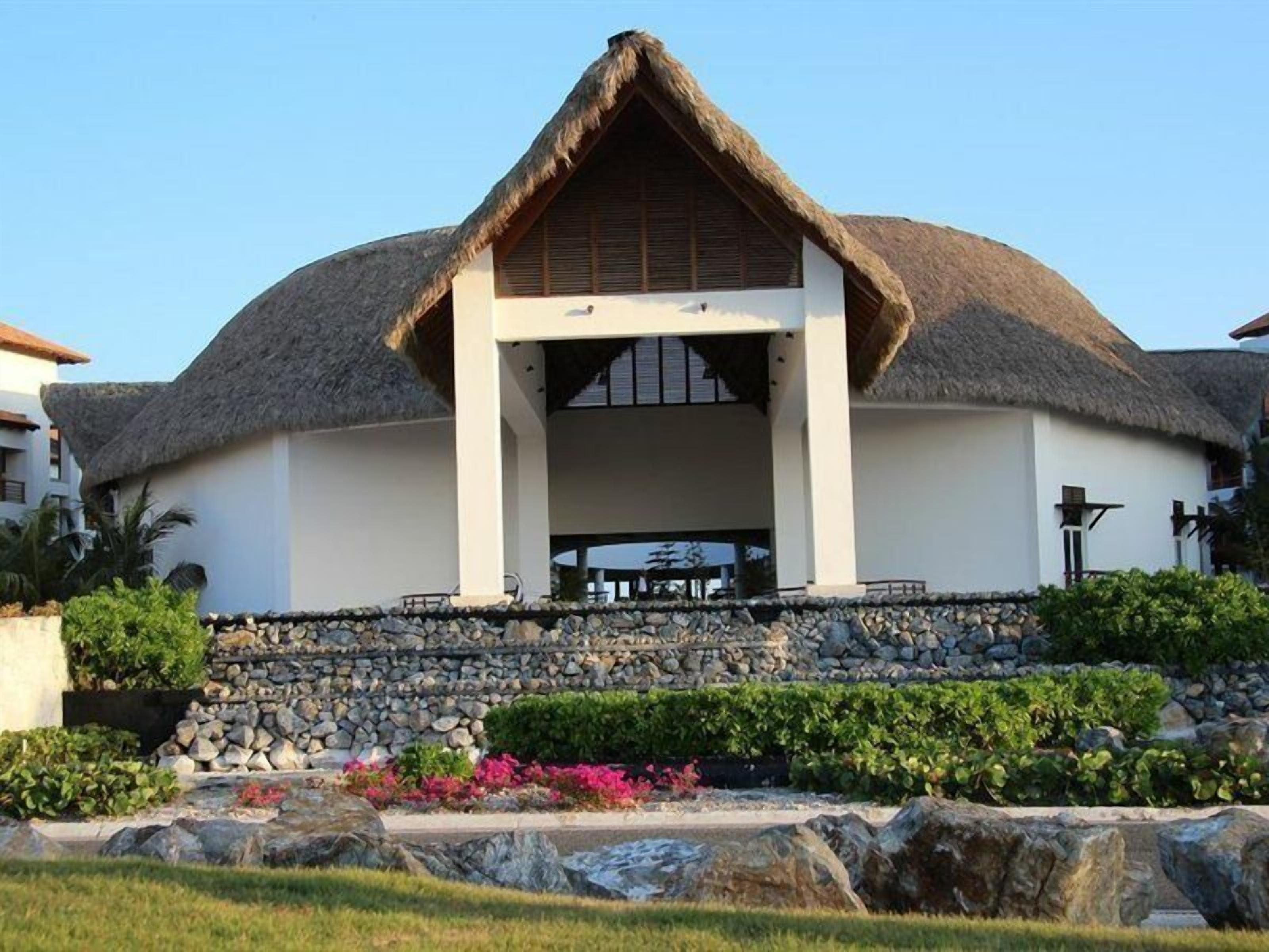 A building with a thatched roof, white walls, and a stone foundation.