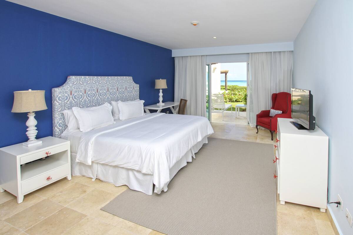 A hotel room with a large bed, a TV, a desk, and a chair.