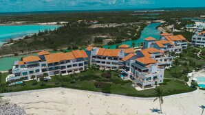 Un resort con varias edificaciones, una playa y una laguna turquesa.