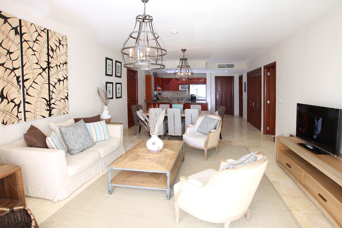 A modern living room with a sofa, armchairs, a coffee table, and a TV.