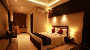 A hotel room with a bed, bedside table, lamp, and an air conditioning unit. - Hotel Mars Classic (Chennai)
