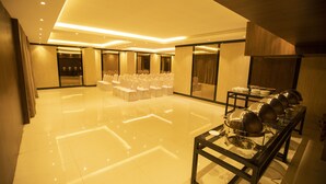 A spacious, well-lit room with a polished floor, rows of white chairs, and a long table with metal bowls. - Hotel Mars Classic (Chennai)
