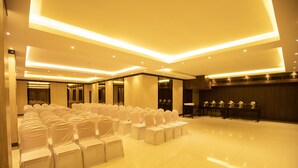 A spacious hall with rows of chairs, a stage, and a long table with items on it. - Hotel Mars Classic (Chennai)