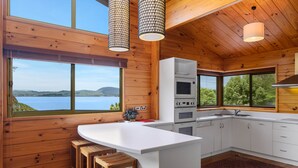 Una cocina moderna con paredes de madera, una isla grande y vista a un lago.