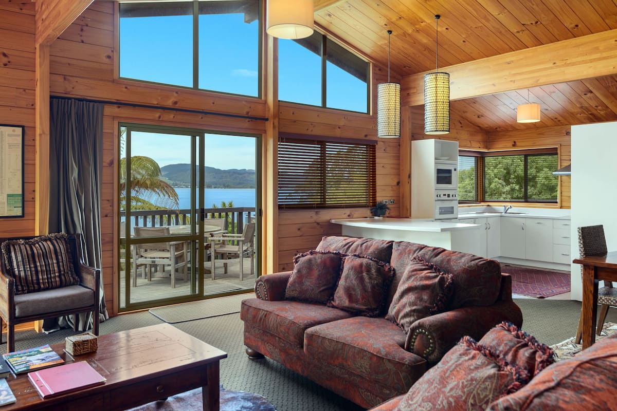 A wooden cabin with a dining area, a sofa, and a kitchen.