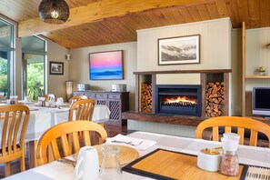 Cozy dining area with a fireplace, wooden furniture, and large windows.