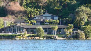 Una propiedad frente al lago con una casa grande, varios terrazas y un patio cubierto.