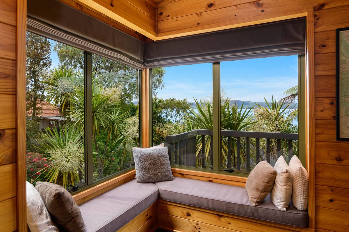 A corner seating area with a view of a garden and distant landscape through large windows.