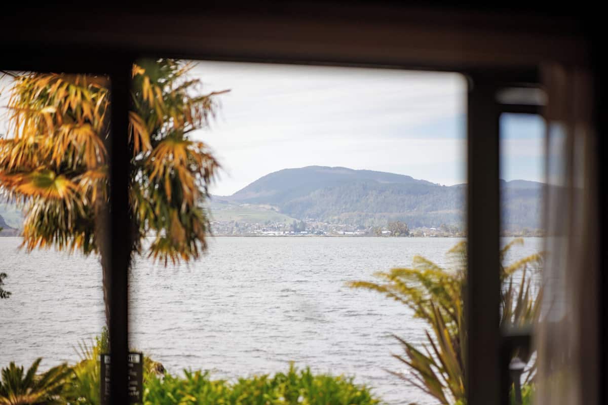 A view of a lake with mountains in the background, viewed from inside a building with a window.