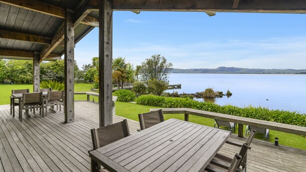 Una terraza de madera con mobiliario exterior y vistas a un lago.