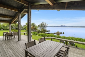 Relax on the spacious deck, overlooking a tranquil body of water, with tables and chairs for dining or socializing.