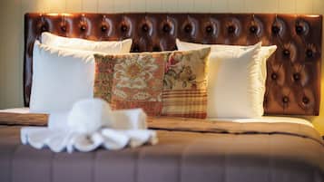 A bed with a brown headboard, white pillows, and a floral-patterned throw.