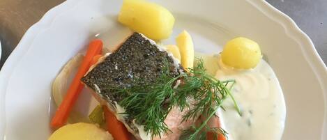 Un plato blanco con un trozo de pescado, zanahorias y patatas.