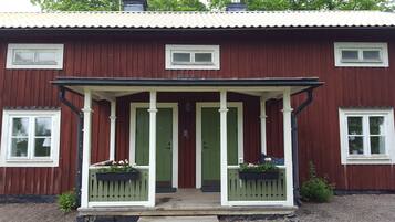 A red wooden house with a porch, green doors, and flower boxes.