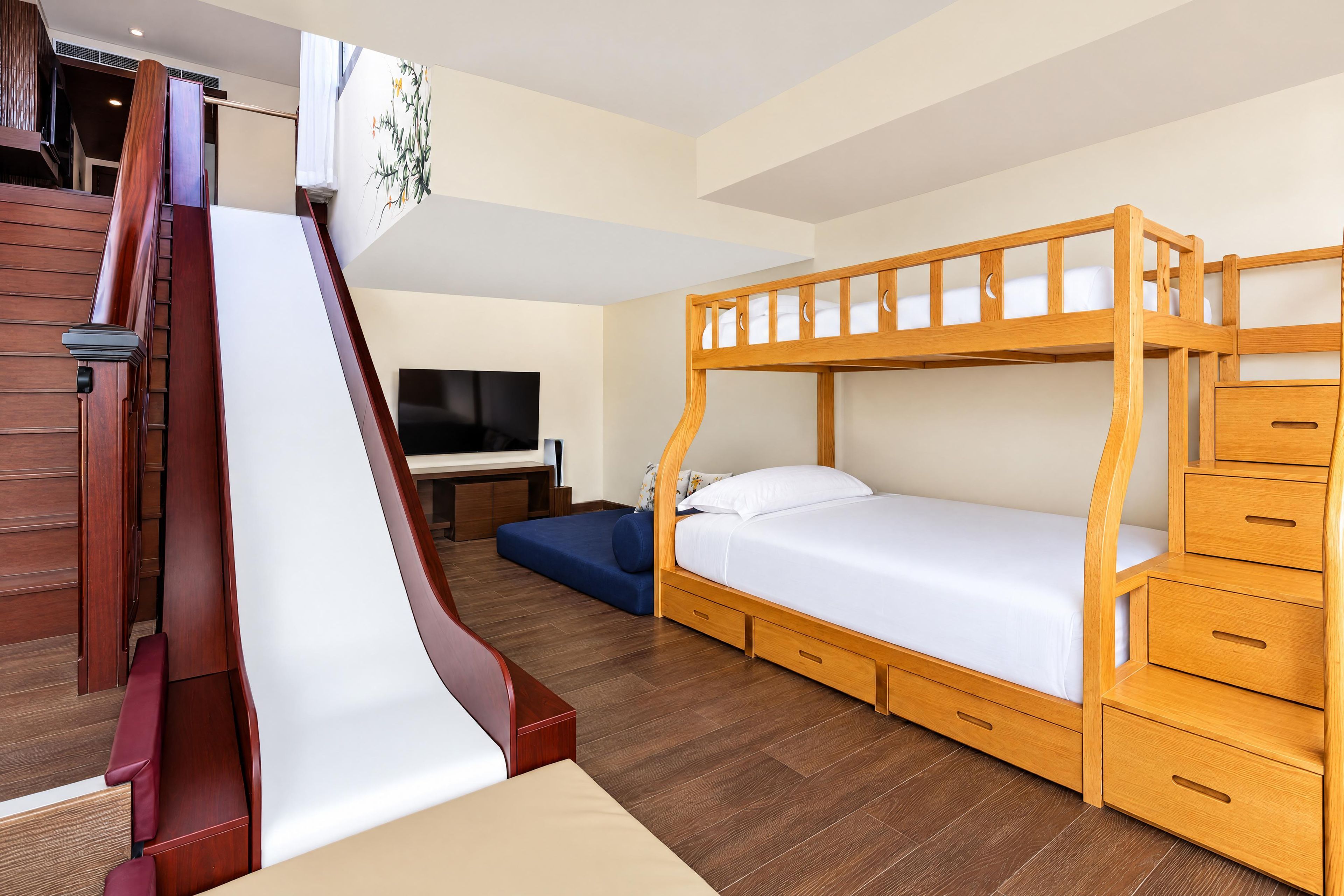 Camera con letto a castello, scala in legno, televisione a schermo piatto e scrivania con sedia.