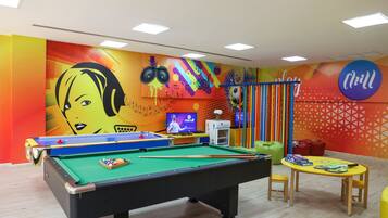 Relax and have fun in this vibrant recreational area with a pool table, colorful artwork, and comfortable seating.