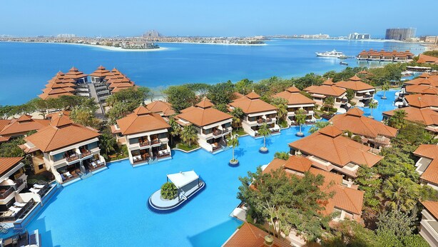 Ein Resort mit mehreren Gebäuden, einem zentralen Schwimmbecken und Blick auf das Meer.