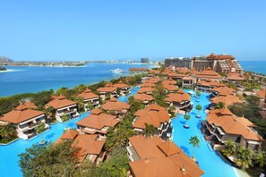 A resort with multiple swimming pools surrounded by villas with red-tiled roofs, overlooking a clear blue sea. - Anantara The Palm Dubai Resort (Dubai)