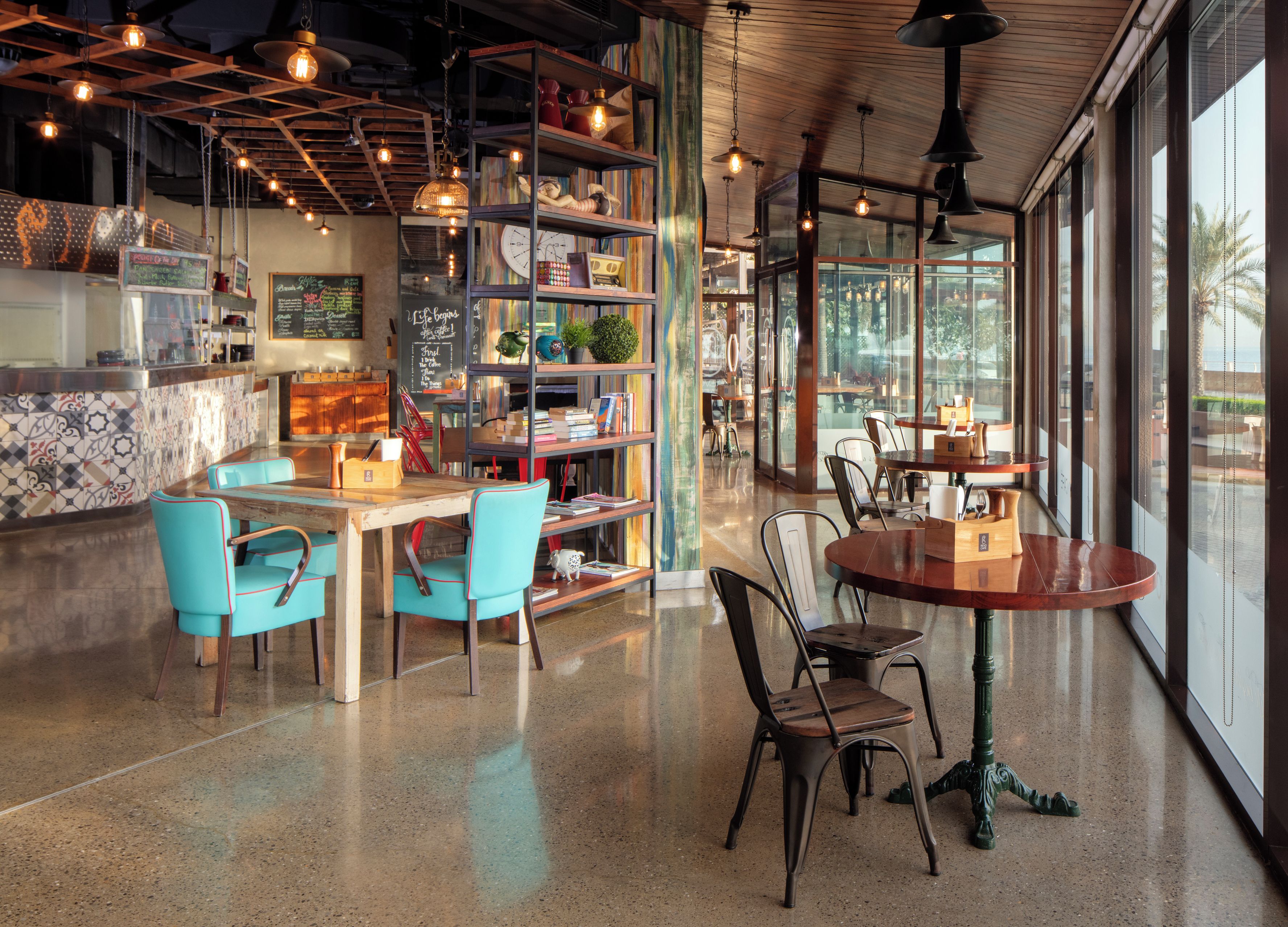 Een modern interieur met houten plafond, zichtbare balken en diverse zitmogelijkheden, waaronder tafels en stoelen.