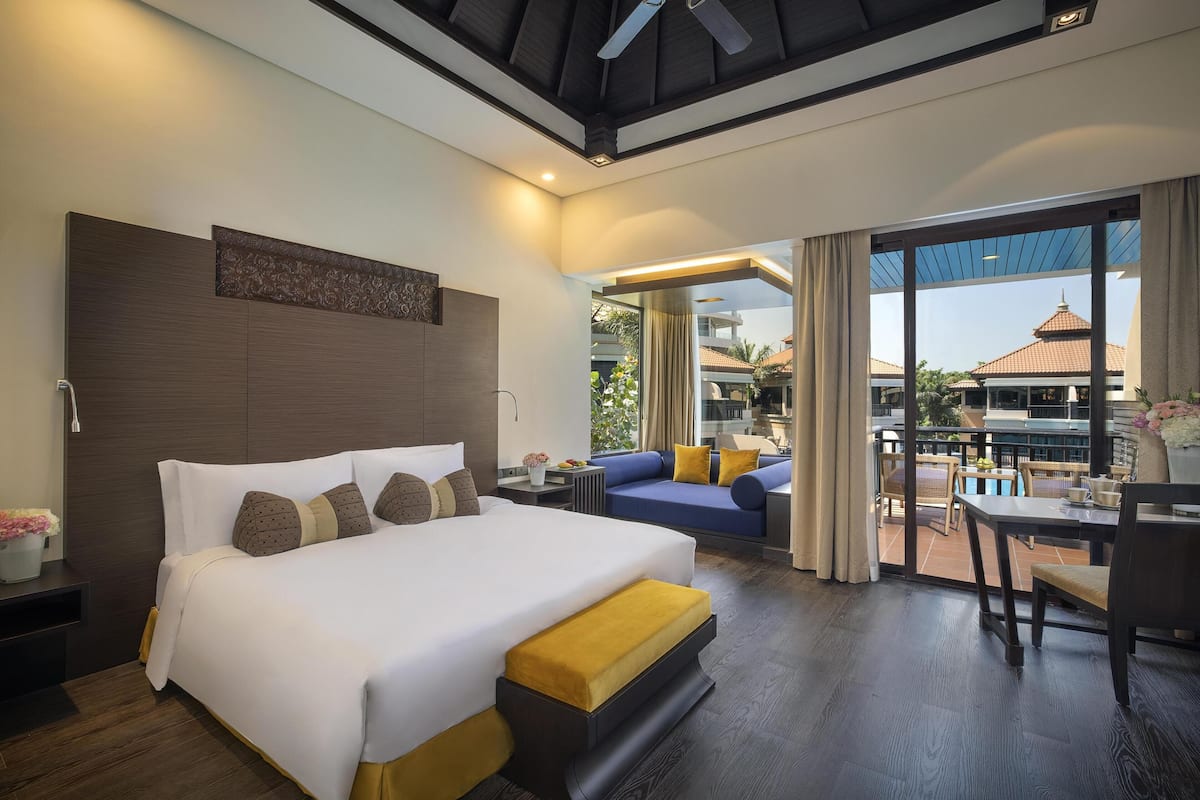 Een hotelkamer met een groot bed, een slaapbank, een eettafel en uitzicht buiten.