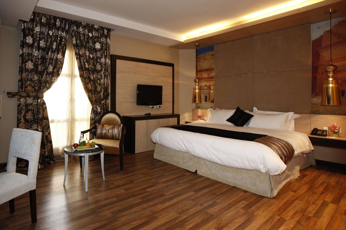 Una habitación de hotel con una cama grande, un escritorio, una silla y un televisor.