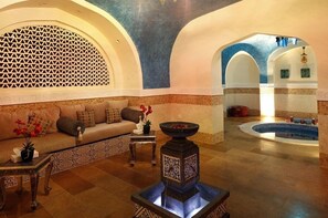 A luxurious spa area with a seating area, a decorative fountain, and a swimming pool.
