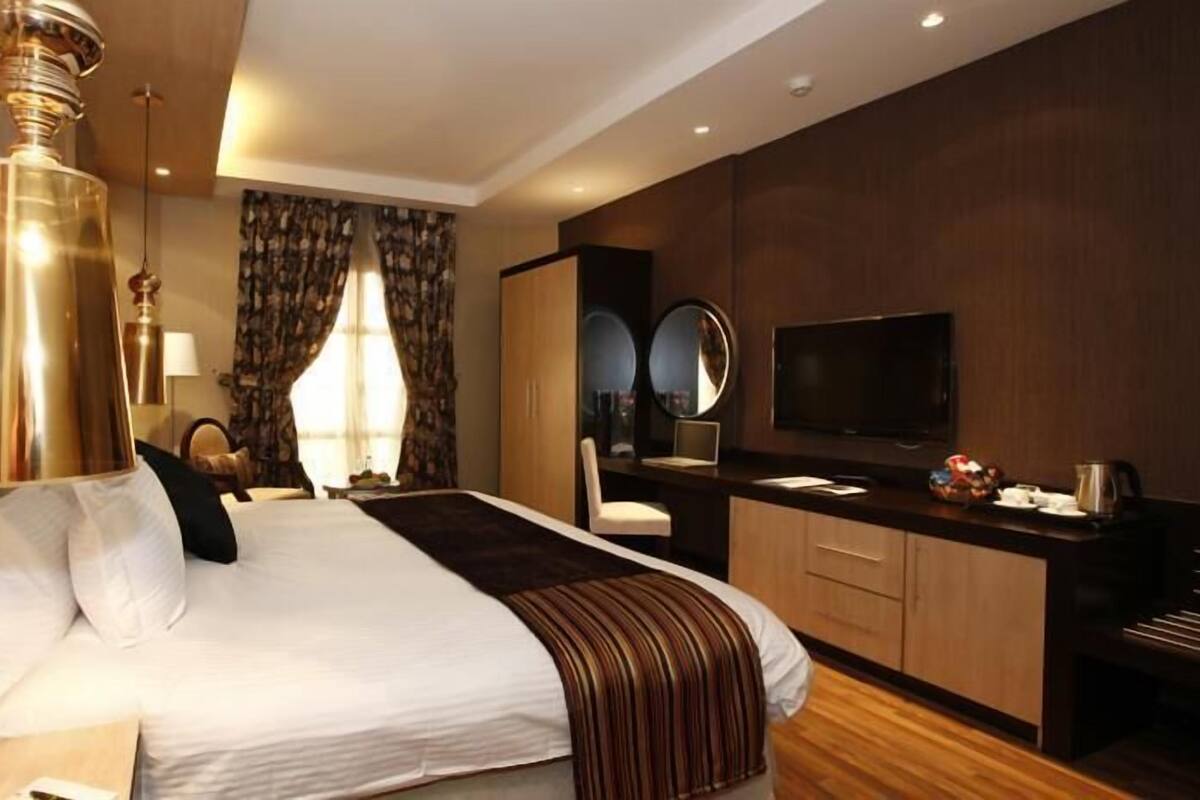 Una habitación de hotel moderna con una cama grande, un escritorio, un televisor y un minibar.