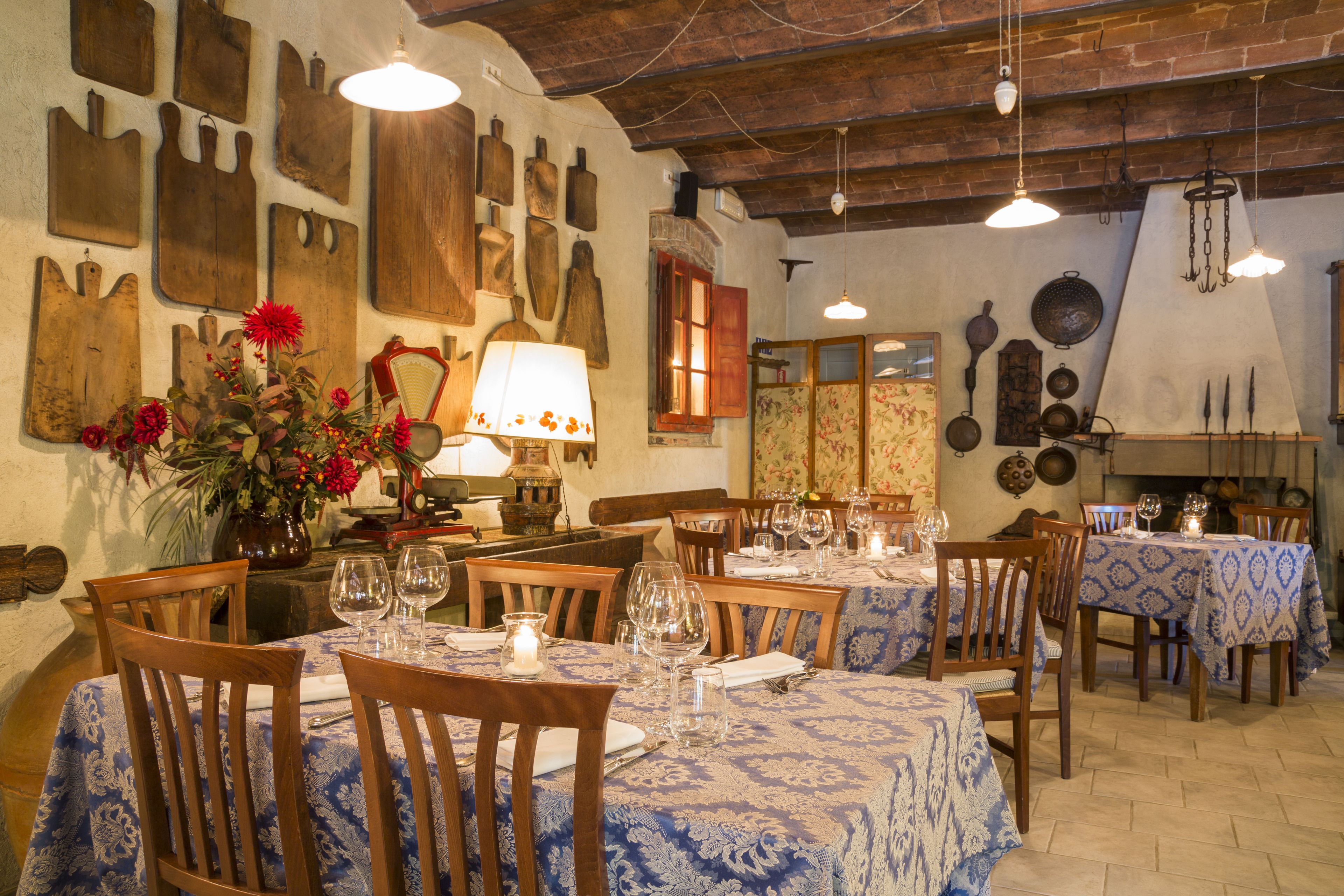 A dining area with wooden tables and chairs, covered with blue patterned tablecloths, and a variety of wooden wall decorations.