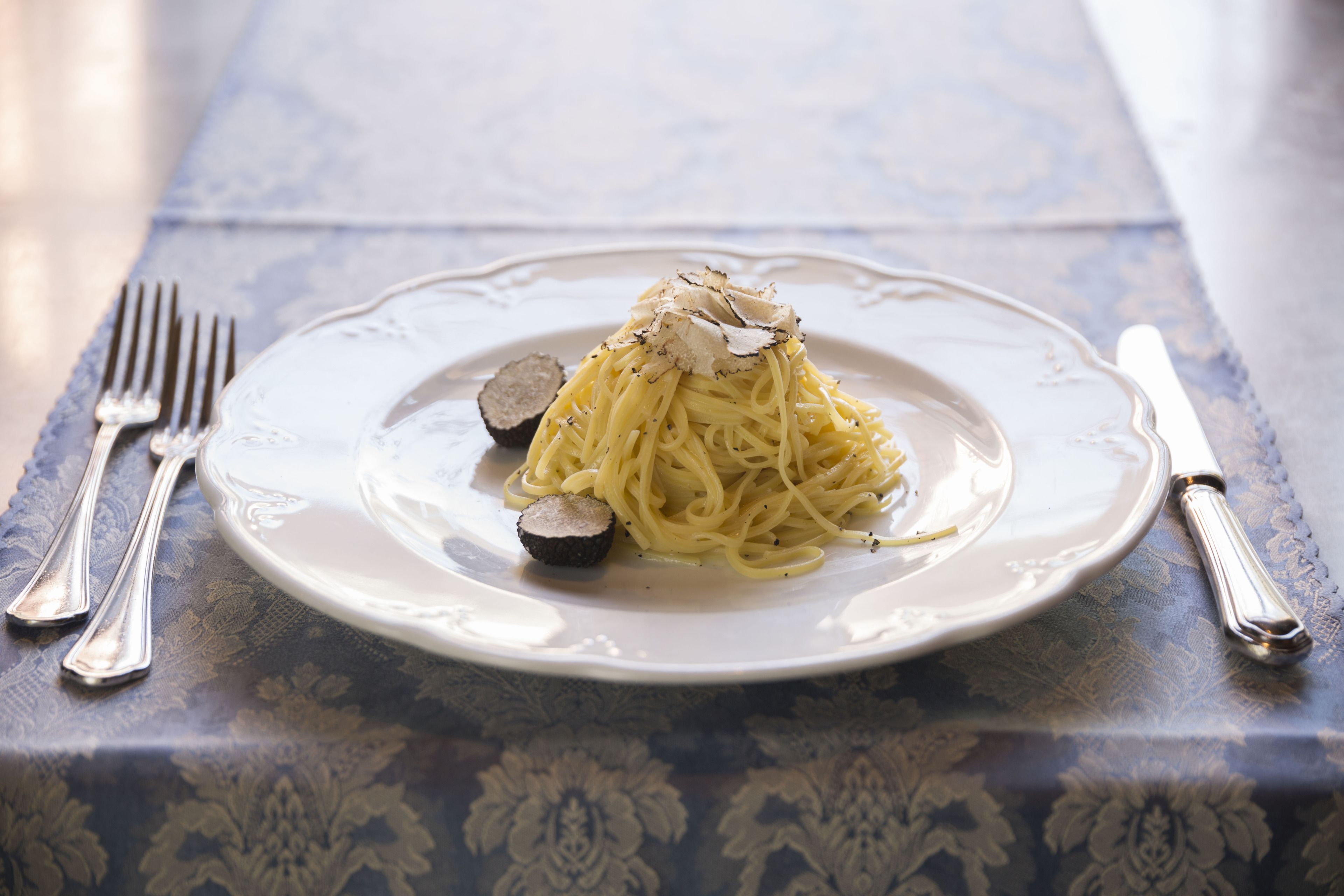 Un plato de espagueti con trufas sobre un mantel.