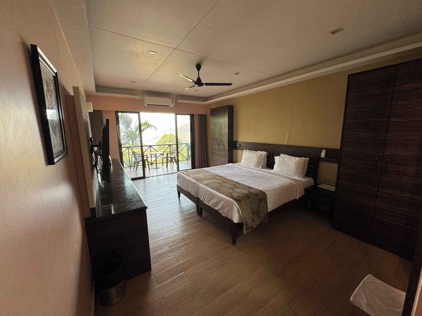 A hotel room with a bed, a desk, a chair, and a balcony with a view.
