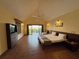 A hotel room with a large bed, a TV, a balcony with a view, and a ceiling fan.