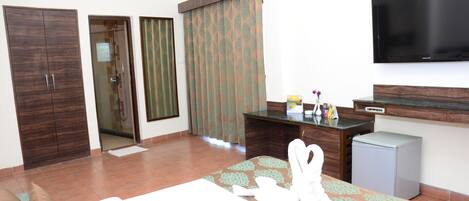 A hotel room with a bed, a desk, a television, a wardrobe, and a bathroom.