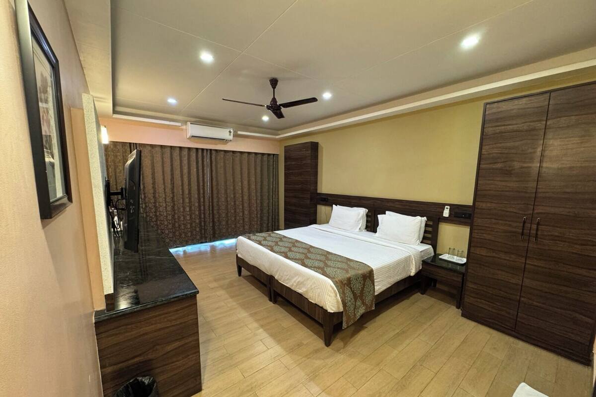 Une chambre d’hôtel équipée d’un lit, d’un bureau, d’une armoire et d’un ventilateur de plafond.