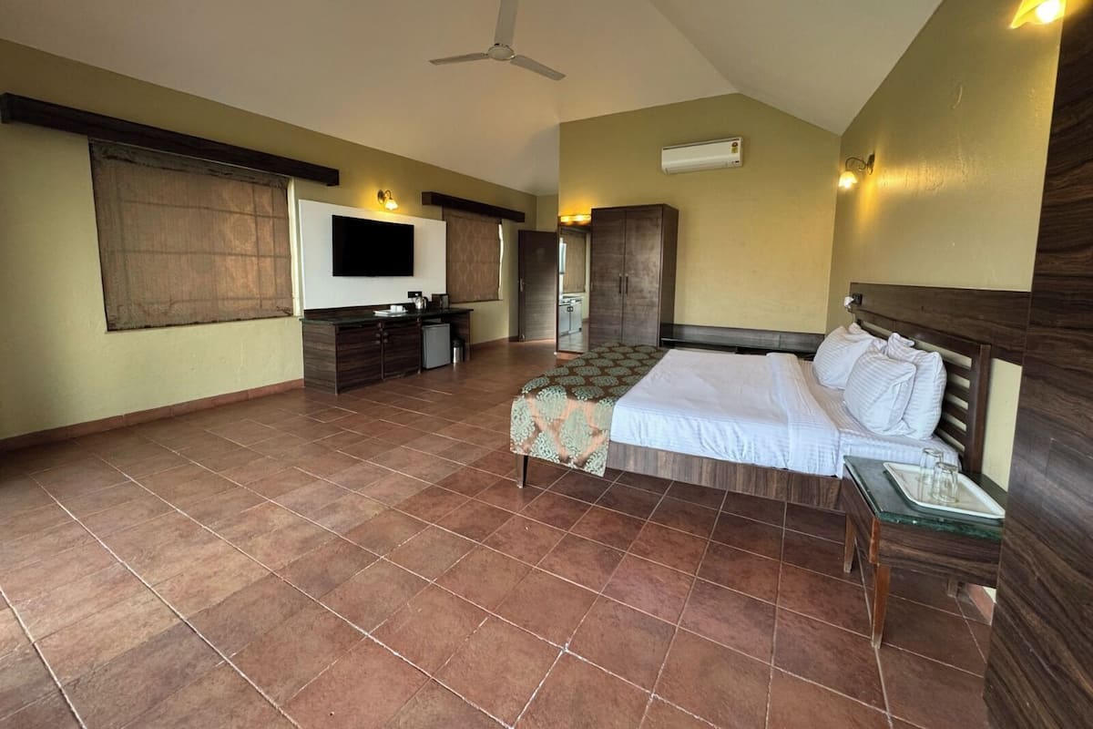 Une chambre spacieuse avec un grand lit, un bureau, une armoire et un téléviseur.