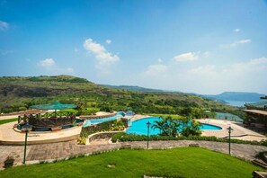 Un resort con una piscina grande, un puente y vistas de las colinas circundantes.