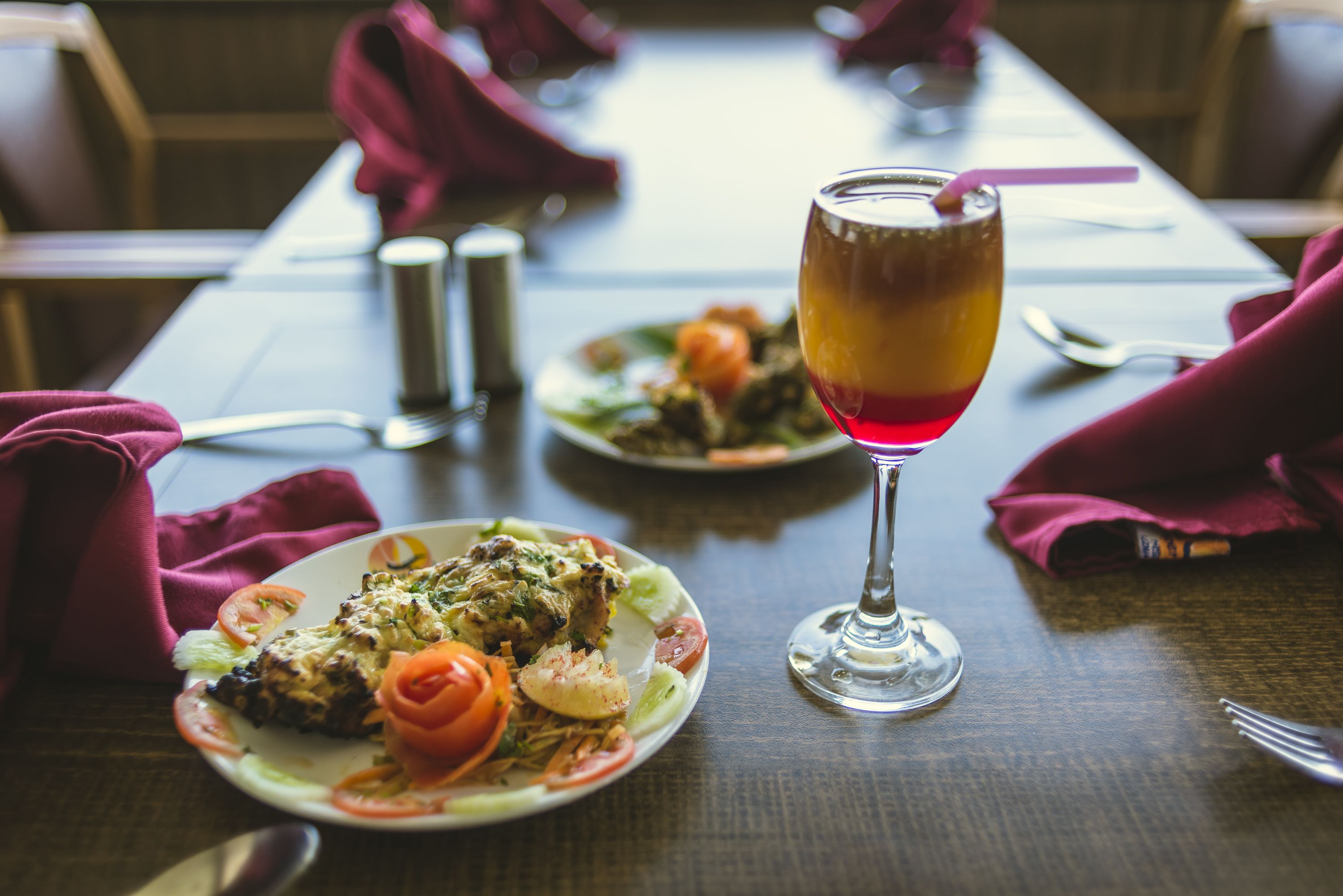 A dining table with plates of food and a glass of drink.