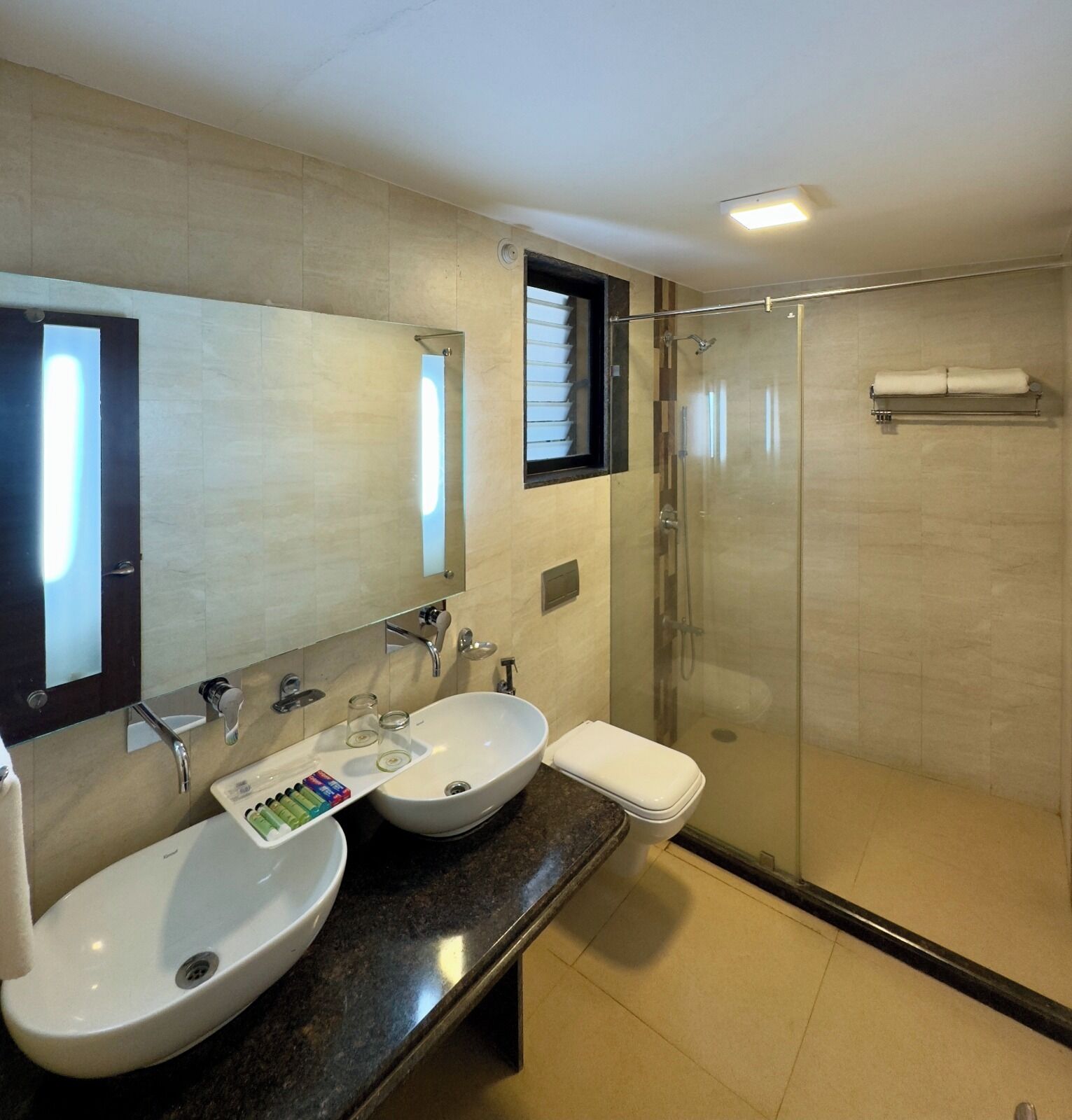 Un bagno moderno con due lavabi, cabina doccia in vetro e un grande specchio.