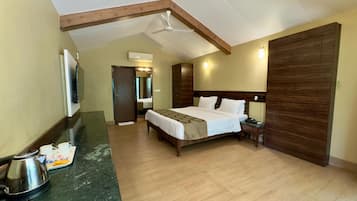 A hotel room with a bed, a nightstand, a coffee maker, a wooden wardrobe, and a ceiling fan.