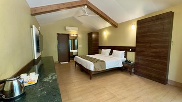 A hotel room with a bed, a nightstand, a coffee maker, a wooden wardrobe, and a ceiling fan.