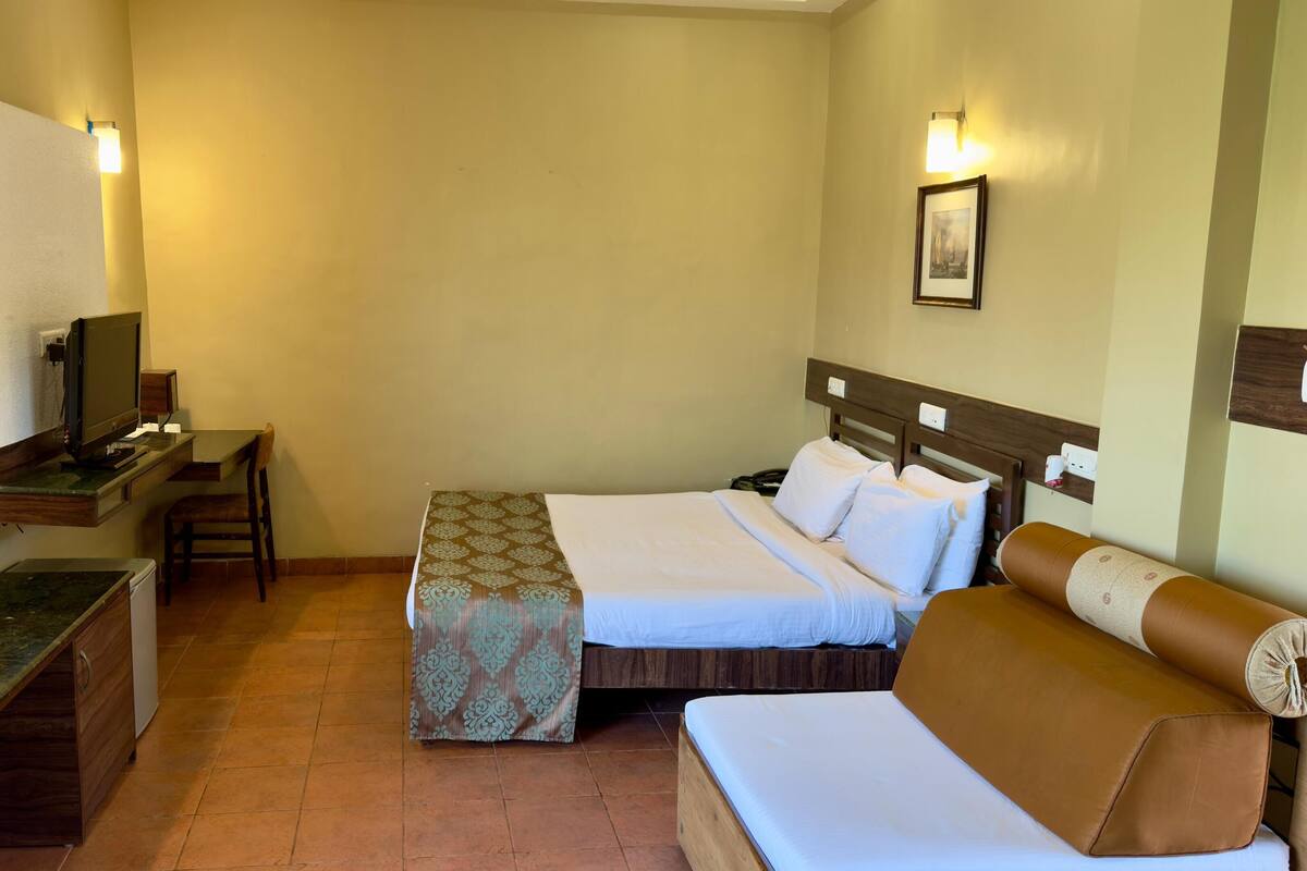 Une chambre d’hôtel avec un lit, un bureau avec un ordinateur, une chaise et un canapé.