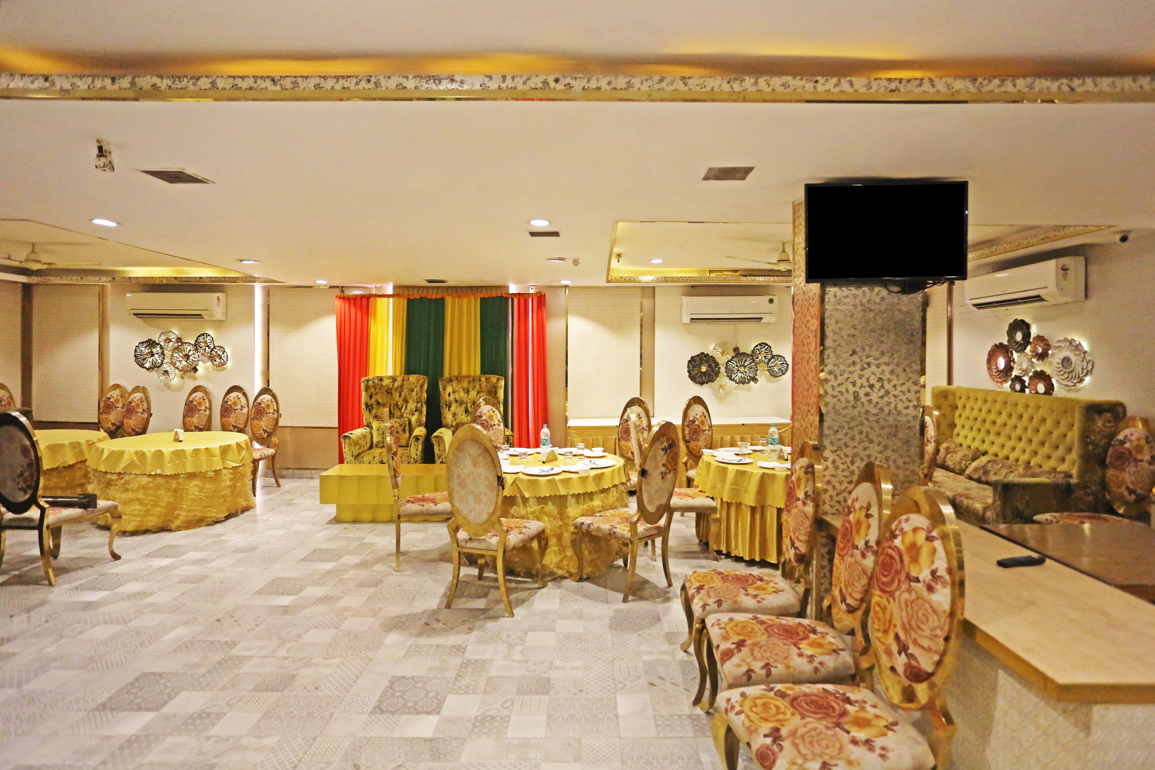 Une salle de banquet avec des tables rondes, des chaises et un coin salon avec des canapés.