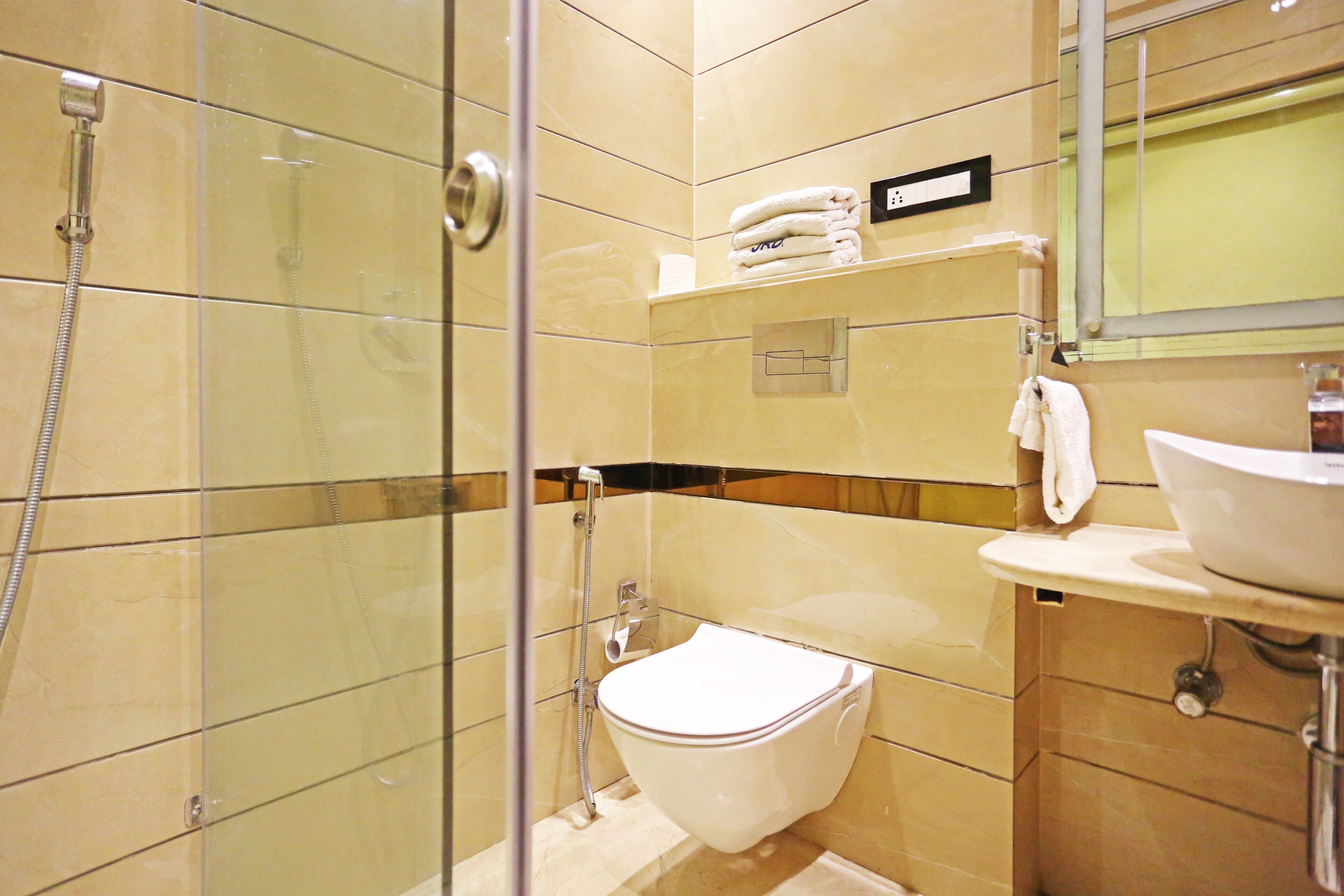 A modern bathroom with a glass-enclosed shower, a white toilet, and a sink with a mirror above it.