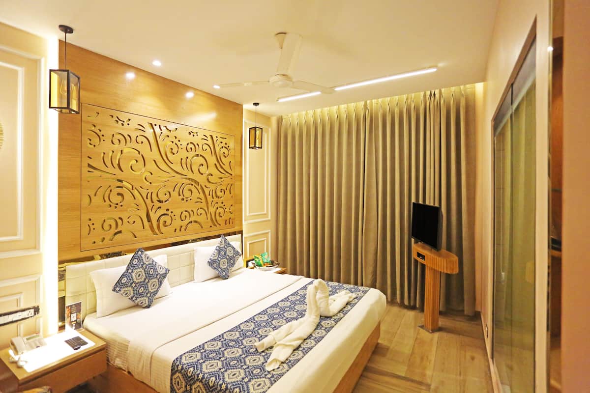 Habitación de hotel con una cama grande, un televisor de pantalla plana, un ventilador de techo y un panel decorativo en la pared.