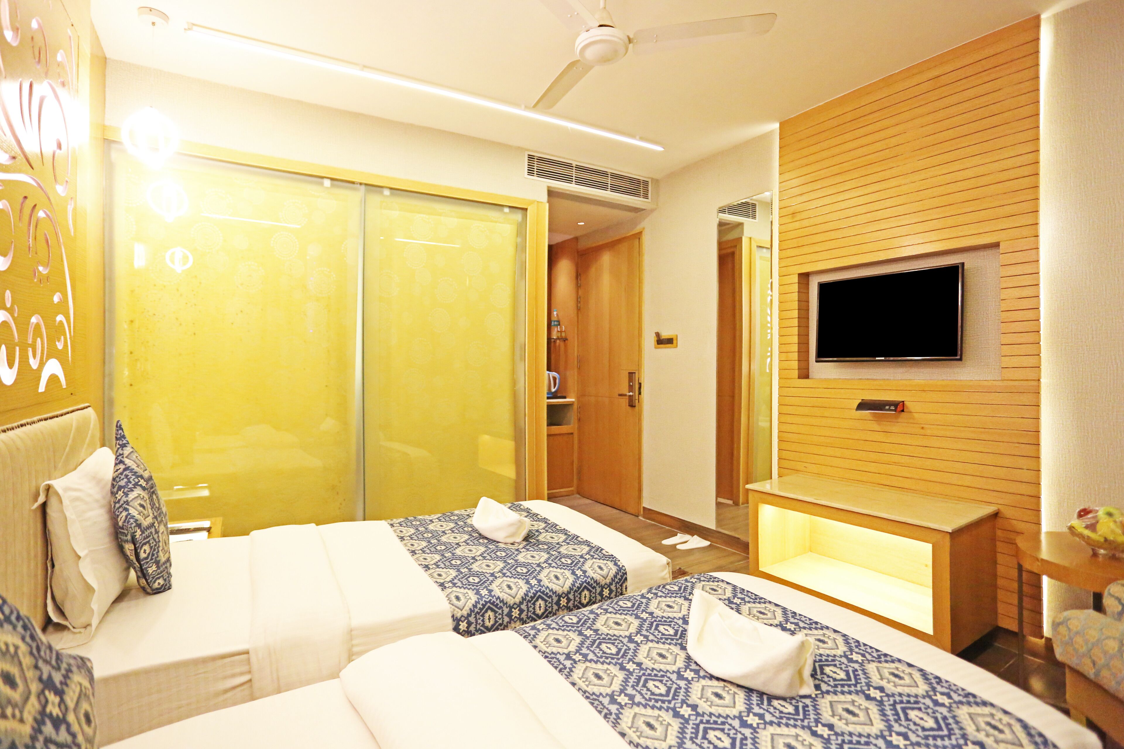 A hotel room with two beds, a TV, and a wooden panel wall.